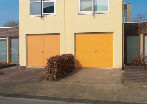 two yellow garage doors in the lower part of a house