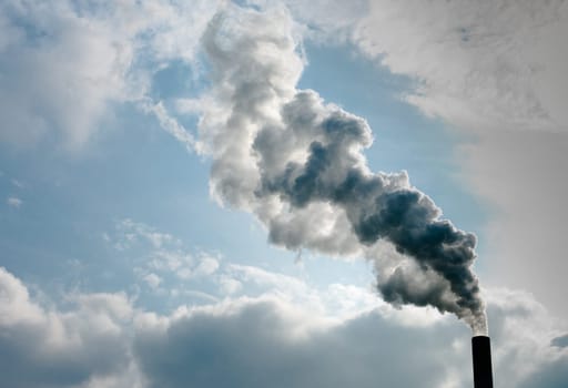smoking chimney of a power plant against a blue sky