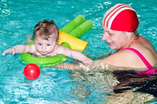 Young family with baby having fun in the swimming pool