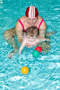 Young family with baby having fun in the swimming pool
