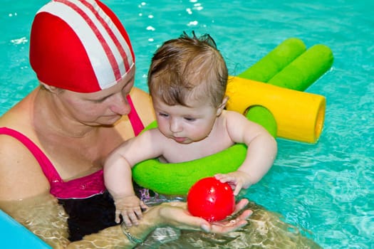Young family with baby having fun in the swimming pool
