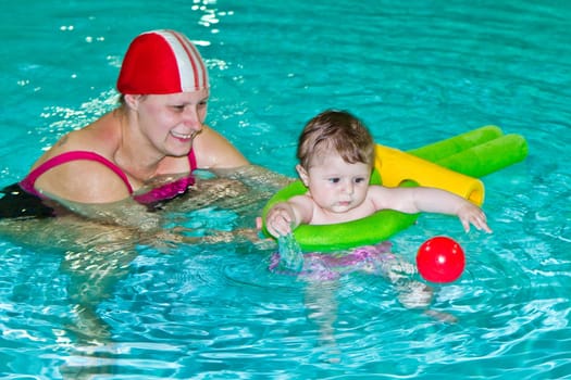 Young family with baby having fun in the swimming pool