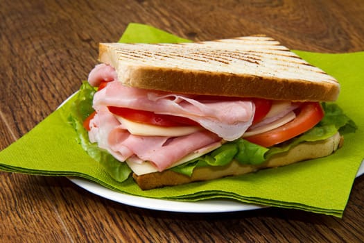 big sandwich with ham, cheese, tomatoes and salad on toasted bread