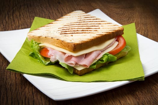 big sandwich with ham, cheese, tomatoes and salad on toasted bread