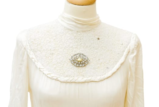 Genuine 1930 white satin bride dress. Jewellery vintage brooch with diamonds. Detail on the lace. Isolated over white background.