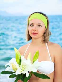 Beautiful woman near the ocean with flowers