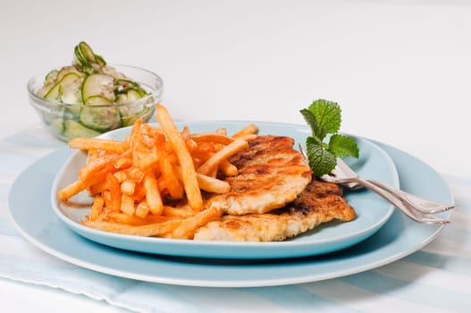 Fish fillet with fries on blue plate