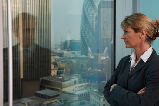 Business woman looking out of window with reflection of business man looking back