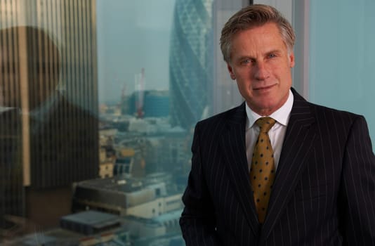 Portrait of a senior executive by a window smiling looking at camera