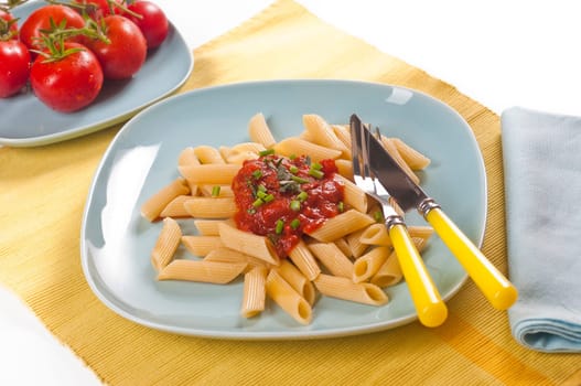 Pasta with tomato sauce and fresh chives on blue dishes