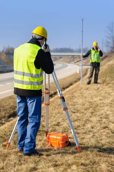 Land surveyors measuring with tacheometer speaking through transmitter highway
