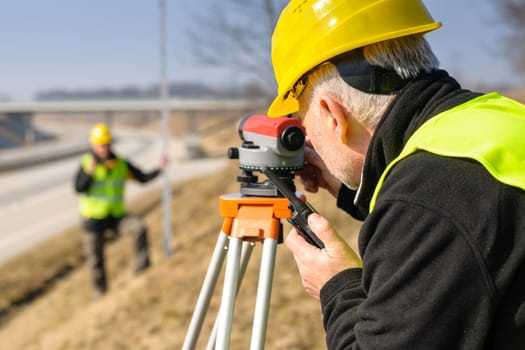 Land surveyors on highway measuring with theodolite
