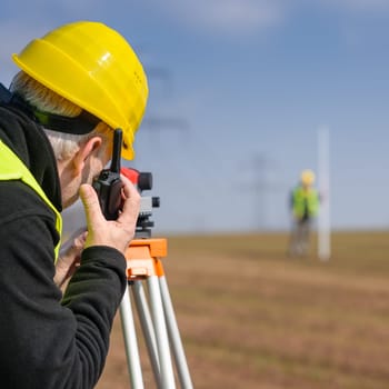 Land surveyors measuring land with tacheometer speaking through transmitter