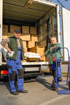 Two male movers unload furniture and boxes from moving truck