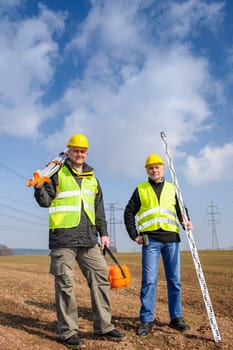 Portrait of two geodesist holding measuring equipment on construction site