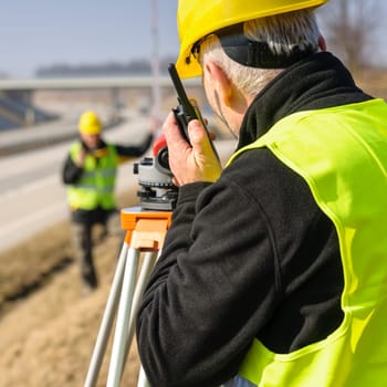 Land surveyors on highway measuring with theodolite
