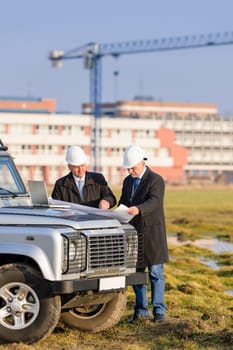 Two architect developers reviewing building plans at construction site
