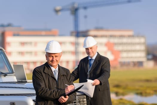 Male architect developers on construction site making notes building project
