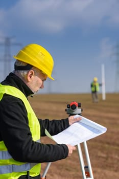 Land surveyors on construction site reading plans measure tacheometer