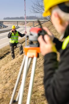 Land surveyors on highway measuring with theodolite