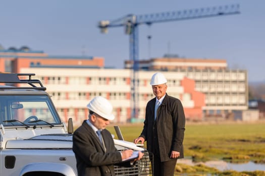 Male architect developers on construction site making notes building project