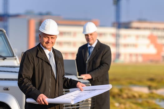 Two architect developers reviewing building plans at construction site