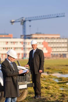 Male architect developers on construction site making notes building project