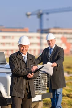 Male architect developers on construction site making notes building project