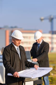 Two architect developers reviewing building plans at construction site