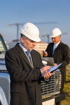 Male architect developers on construction site making notes building project
