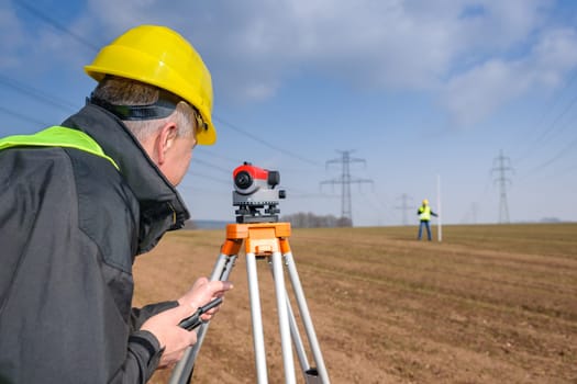 Land surveyors measuring with tacheometer speaking through transmitter
