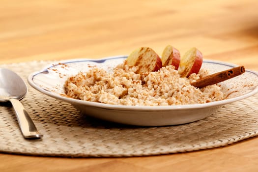 A bowl of apple cinnamon porridge on a wooden table.