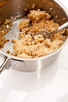 A pot of old cold porridge on a reflective white background