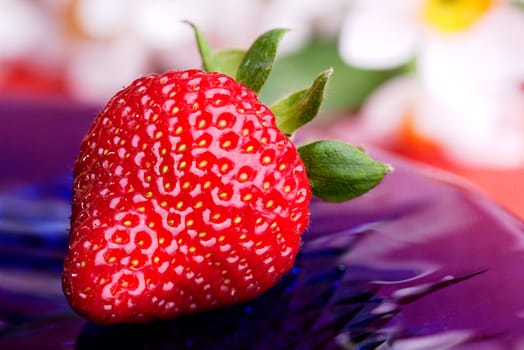A strawberry on a plate in an outdoor setting