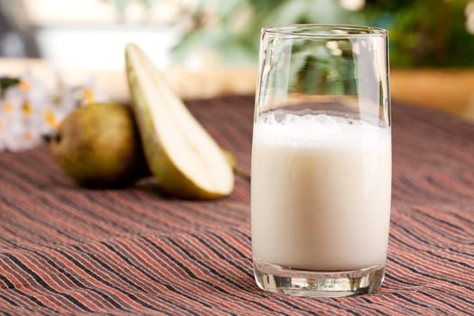 A tall glass of pear smoothie in a natural setting