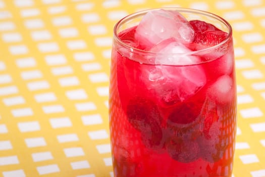 A glass of sparkling raspberry punch outdoors in a natural setting