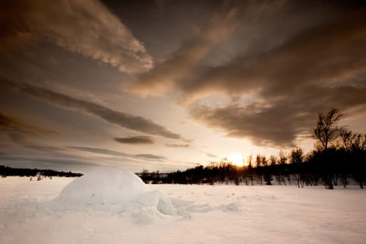 An ingloo against a dramatic sunset