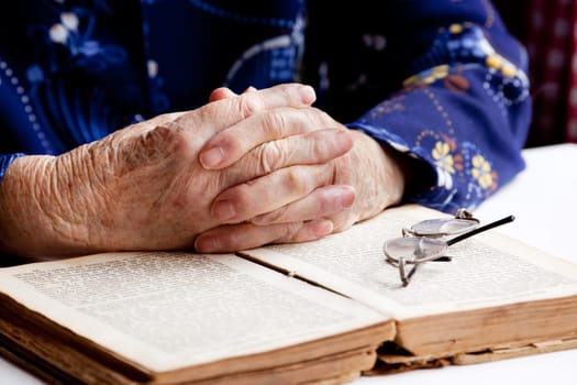 An old pair of hands in prayer on a book