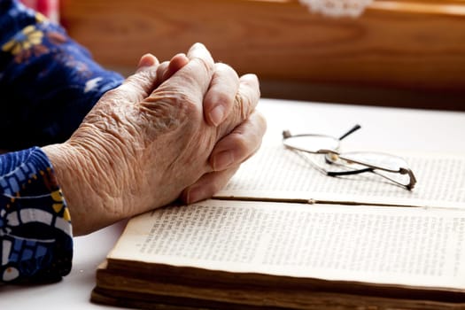 An old pair of hands in prayer on a book