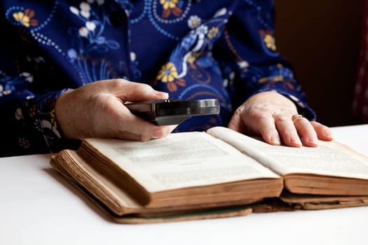 An elderly woman reading a very old book