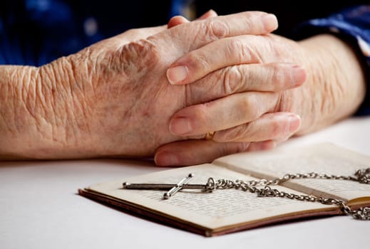 Old female hands with a cross and book