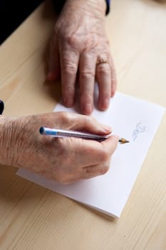 An old pair of hands writing a letter