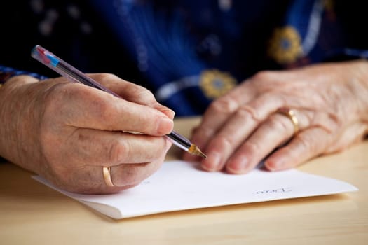 An old pair of hands writing a letter