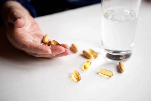 An elderly hand with a variety of large pills