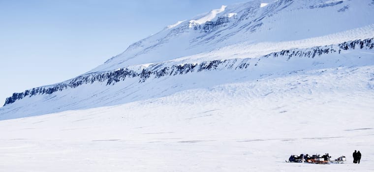 Three snowmobiles and a winter landscape with mountain