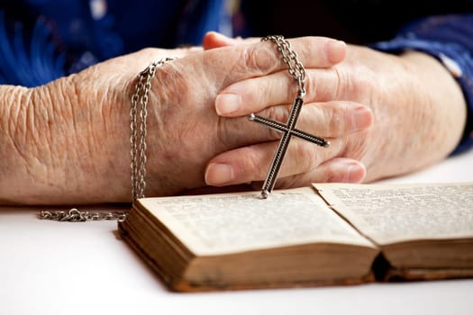 An elderly pair of hands holding a cross