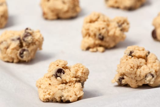 Raw cookie dough on a baking sheet with parchment