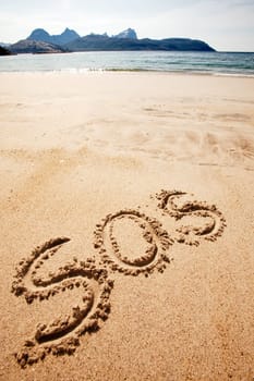 S.O.S written in the sand of an island with the ocean in the distance