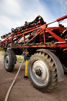 Filling chemical in a high clearance sprayer with proper safety equipment.
