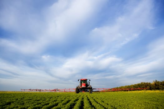 A high clearance sprayer on a field  in a prairie landscape